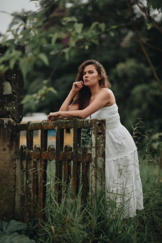 the young woman is leaning on a fence and posing for the camera