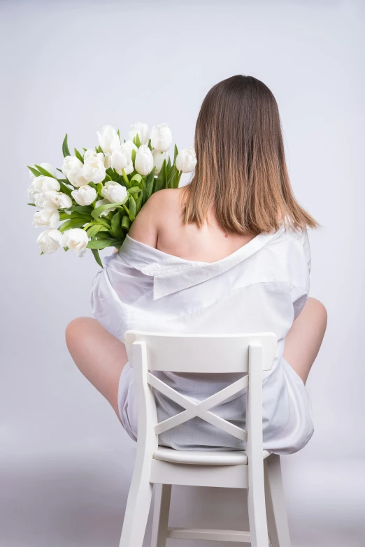 woman in white dress sitting on chair holding bouquet of flowers