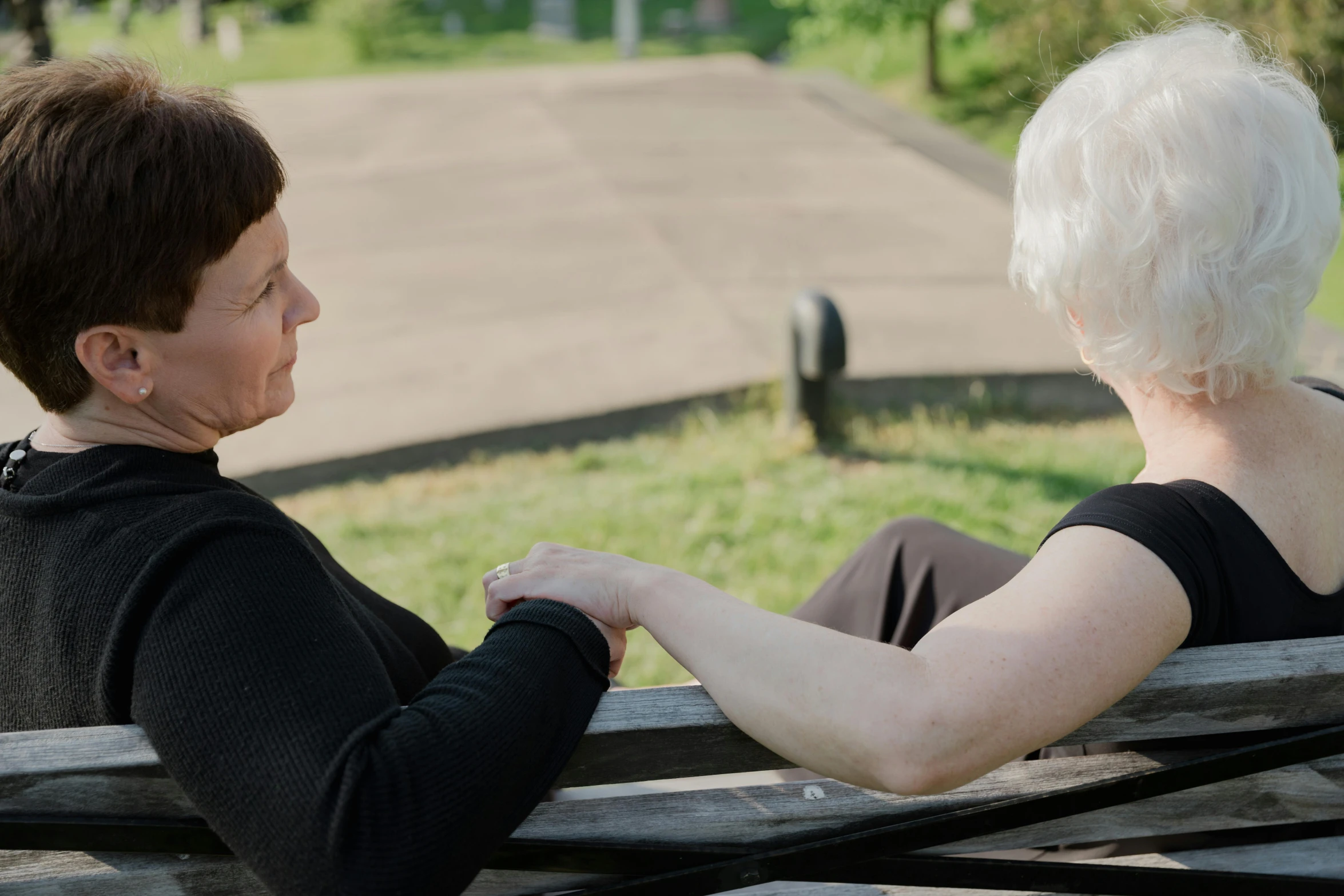 the old lady sits on a bench and looks down at her back