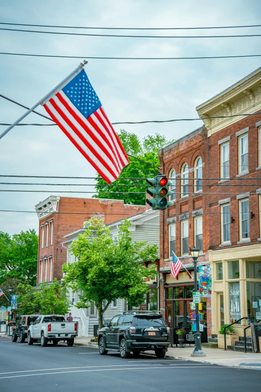 an american flag flies near the stoplights on a city street