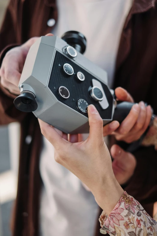 two people holding a camera with ons on each side of the camera