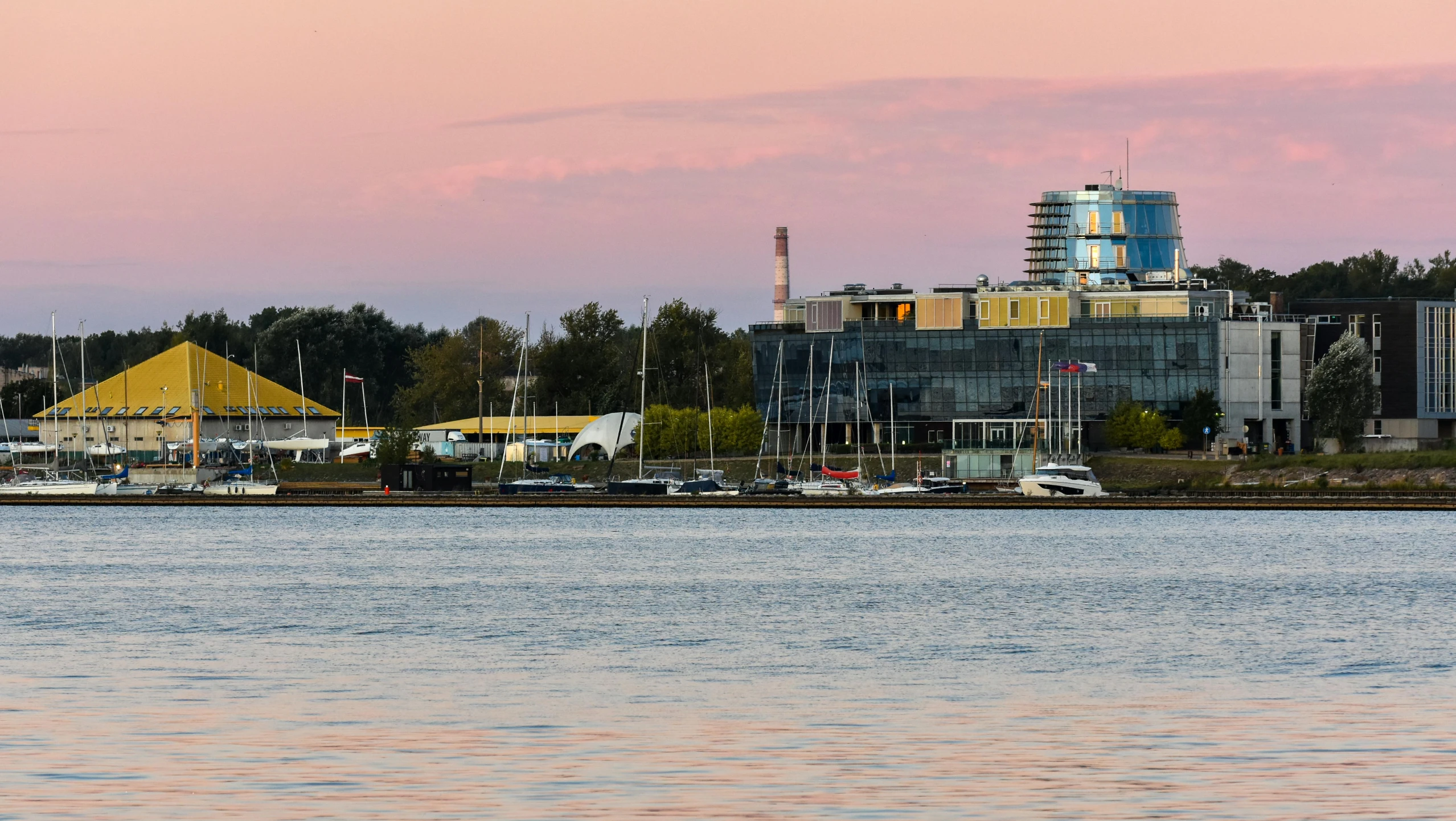 a pink sky and some buildings near water