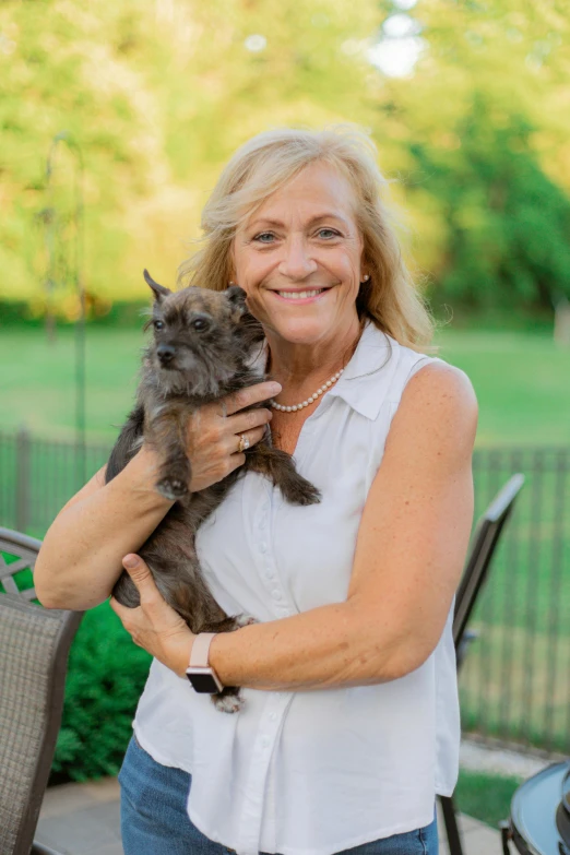 a lady holding a kitten up to her chest