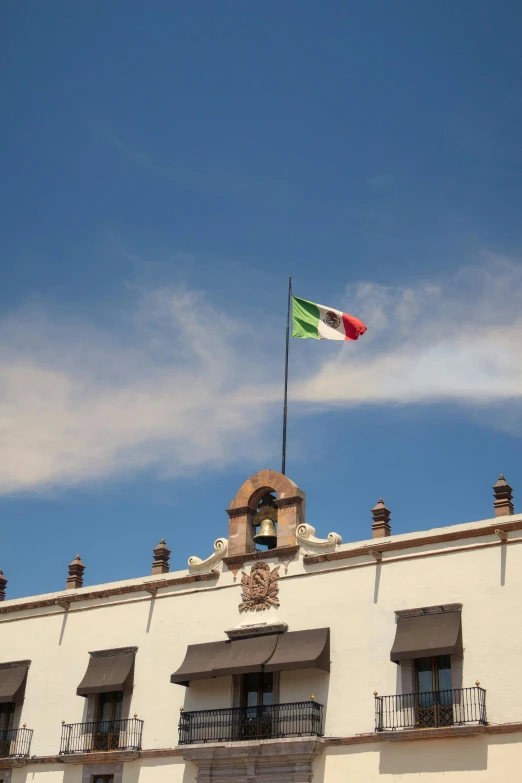 the mexican flag flying atop a building