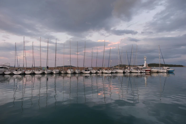 several boats are docked in the ocean on cloudy day