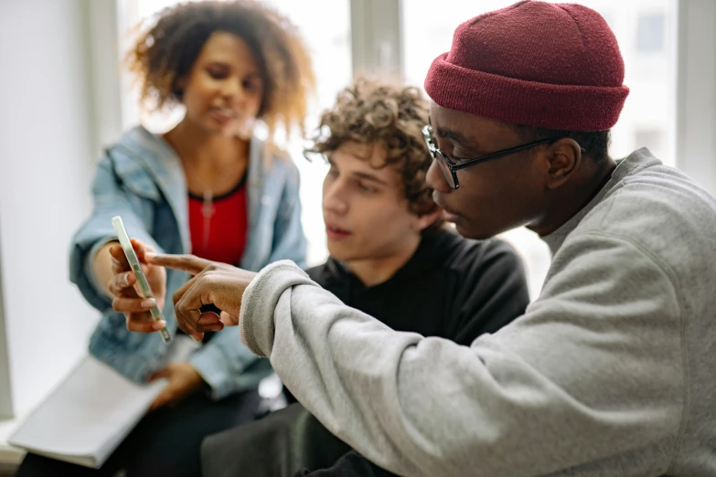 three people sit in a circle and look at their cellphones