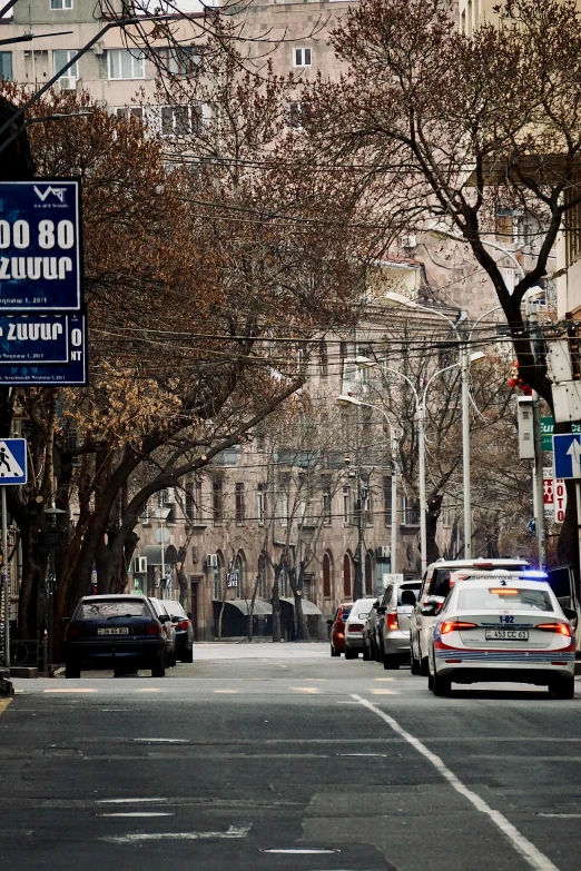 two police cars sitting in traffic at the intersection of a city street