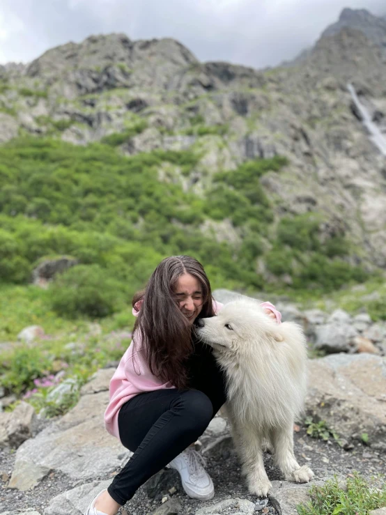 the woman is hugging her pet dog on the rocky surface