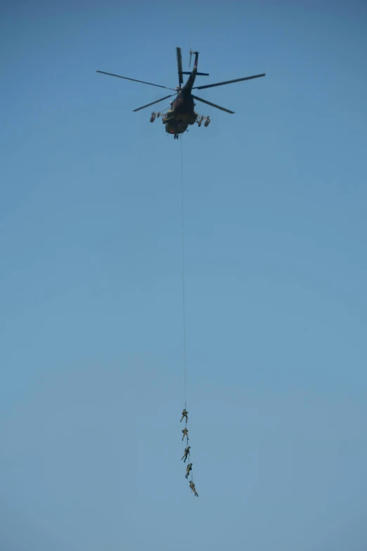 a helicopter is connected to a line attached to an army parachute