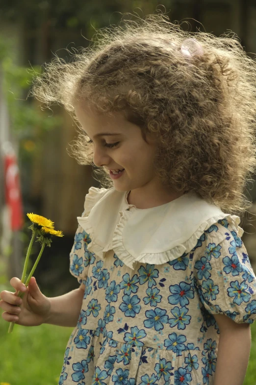 a little girl holding a flower with the background blurry