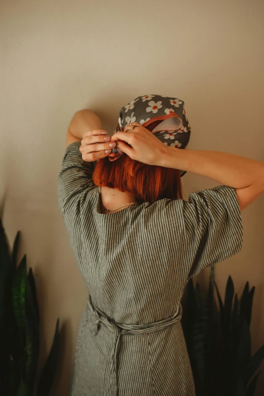 a woman putting on a floral hat is pictured