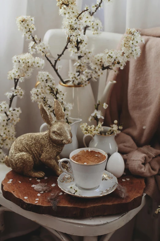 a coffee cup and some tea in front of a vase and flowers