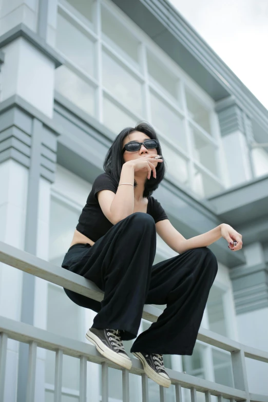 young lady posing on a metal balcony with her hand to her mouth