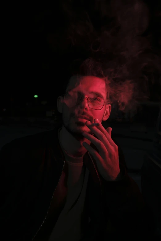 man smoking in the dark, wearing glasses and a leather jacket