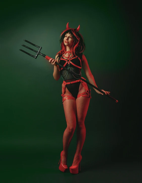 a woman with red hair and black lingerie is posing in her devil costume holding a pitchfork