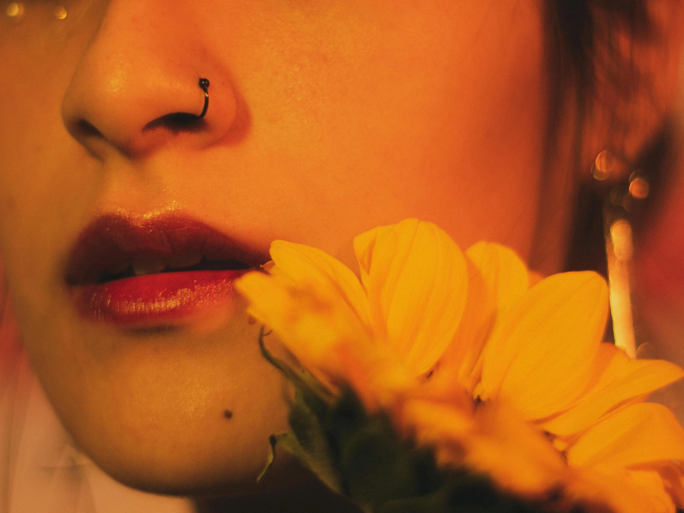 the woman is holding a yellow flower with her nose