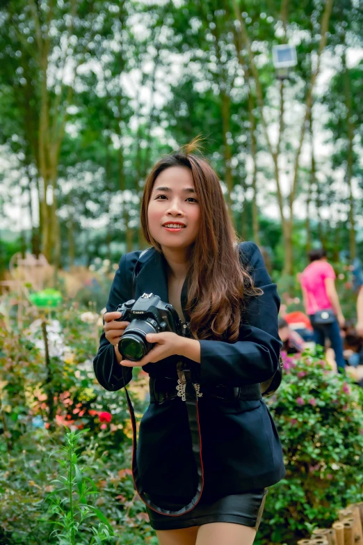 a woman is holding a camera on a flower garden