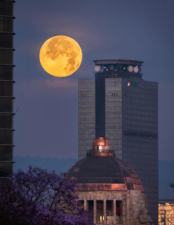 the full moon above a building in the city