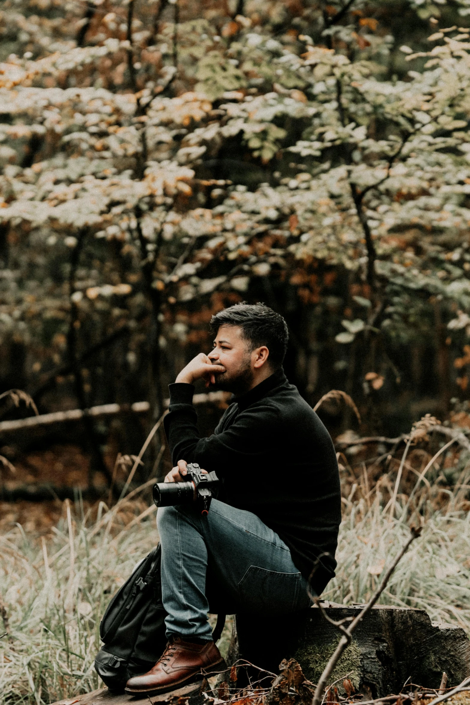 a man sitting on a rock by a fallen tree