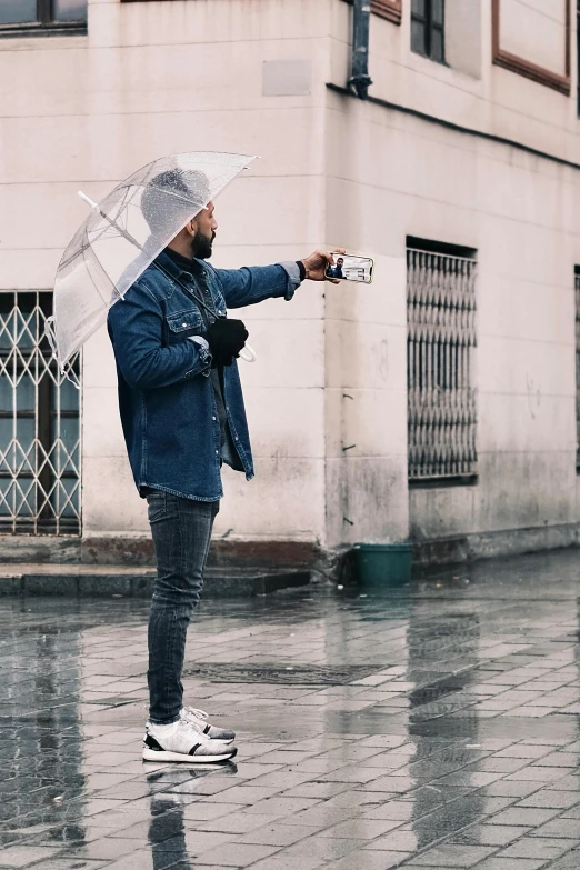 a man in jacket holding an umbrella and taking a po