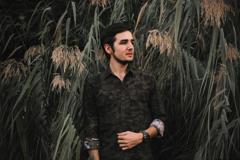 a man in black shirt standing in tall grass