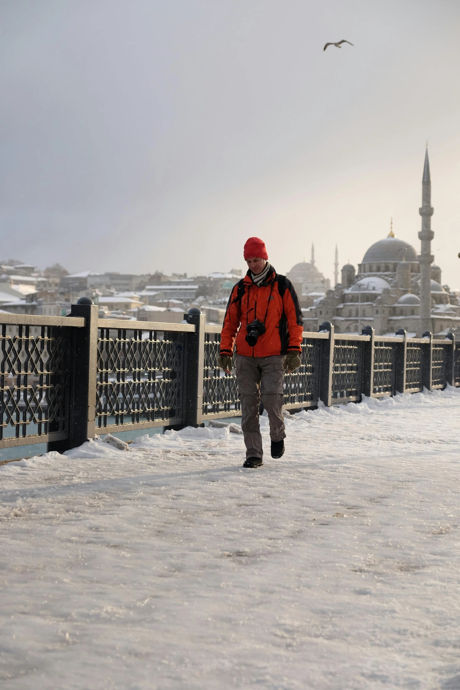 a man walking in the snow next to a fence