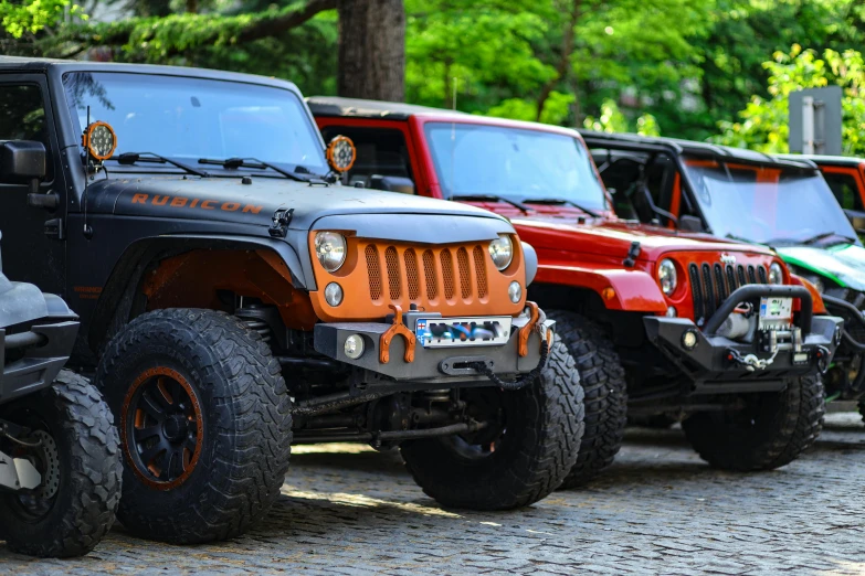 a line up of jeeps parked in front of a forest