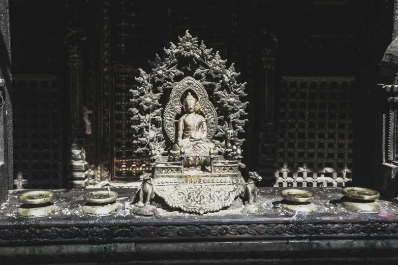 a statue sitting in front of some pots and candles