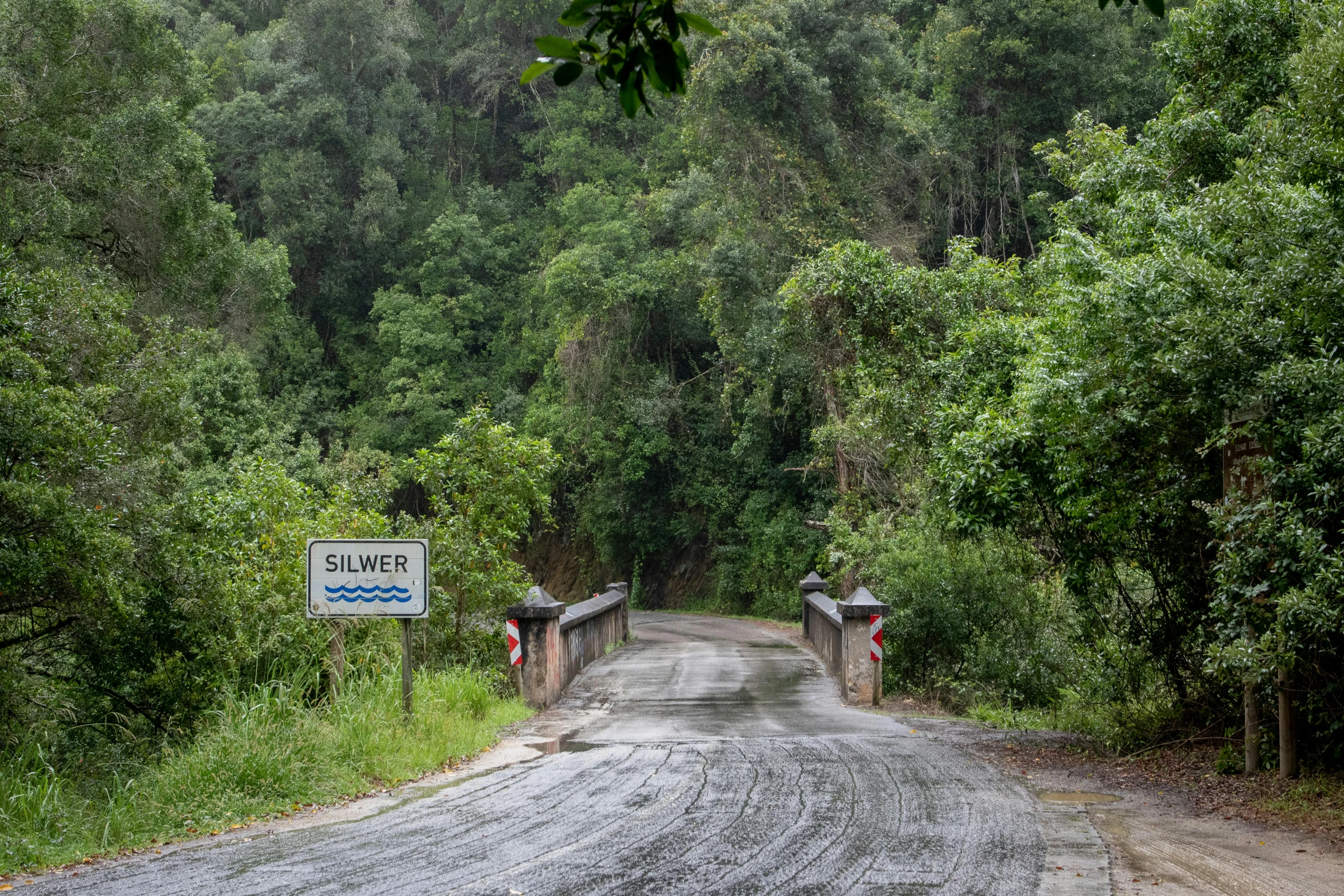 a wooden gate is built to allow people to cross a dirt road