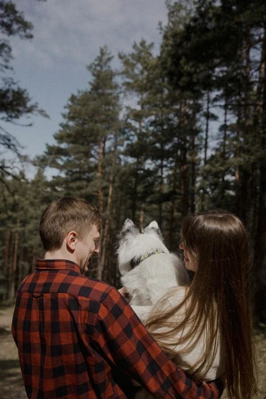 the young couple is looking at the white dog