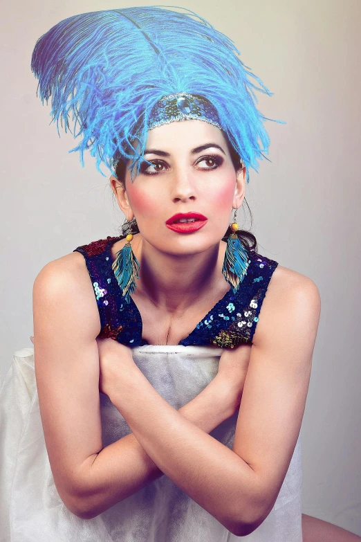 a woman posing in a dress with blue feathers on her head