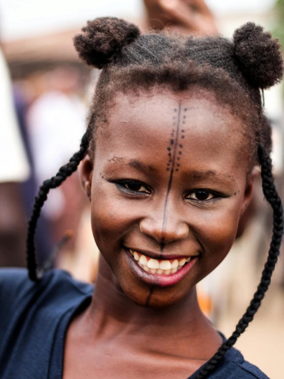 an african child smiling with some small decorations on her face