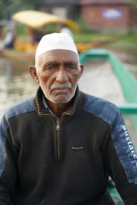 an older man in black shirt sitting by the water