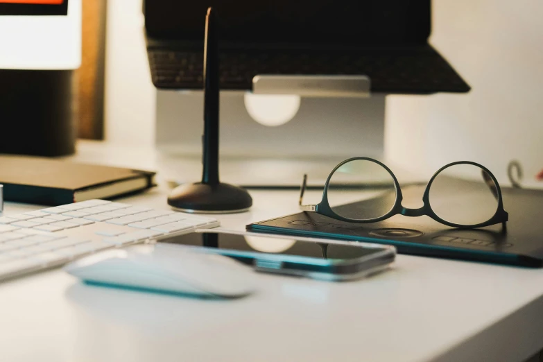 glasses and books are sitting on the desk next to a computer