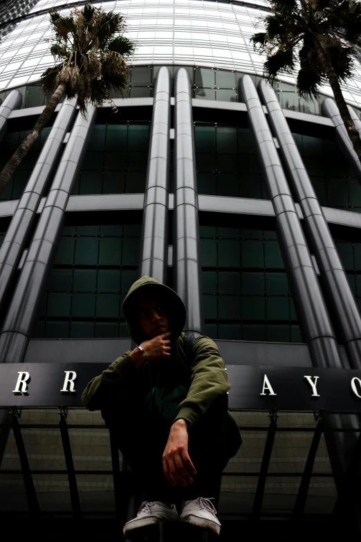 a young man sitting in front of the building