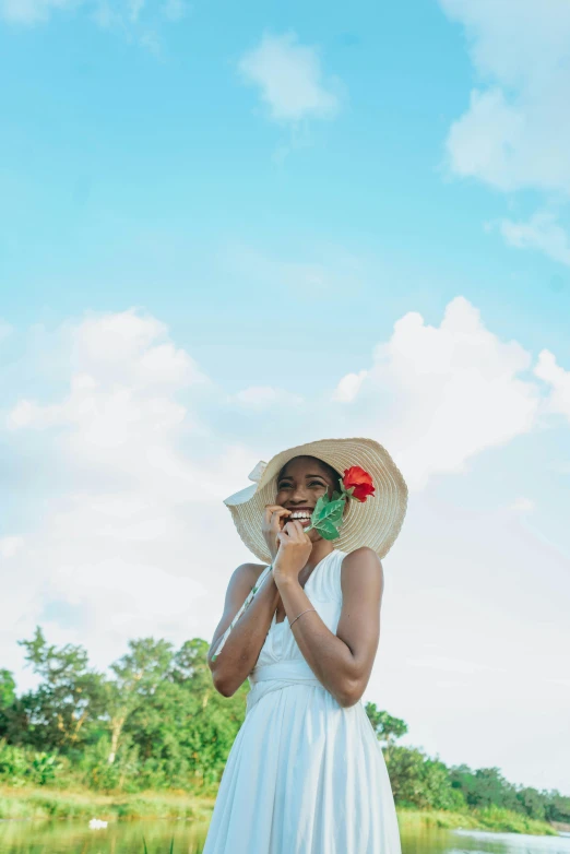 a woman is on her cell phone in a dress and straw hat