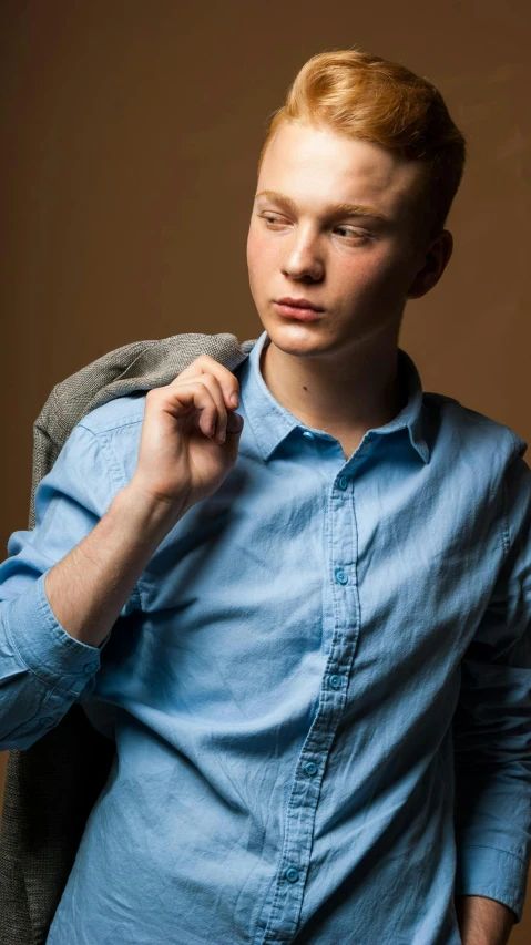 a young man with his head tilted up wearing a blue shirt and jeans