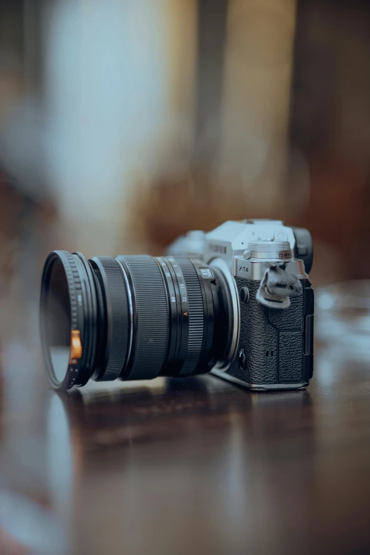 a camera sitting on top of a wooden table next to a cup