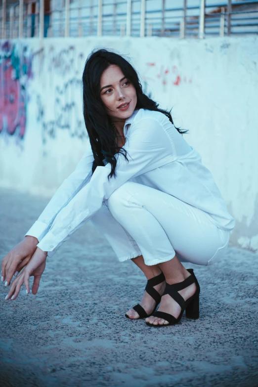a young woman in white poses on concrete