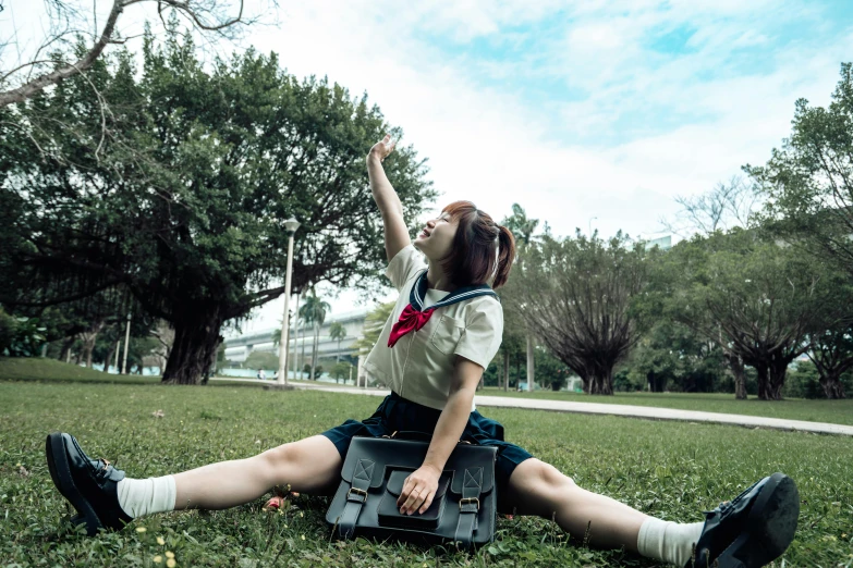 a  sitting on the grass while holding a laptop computer