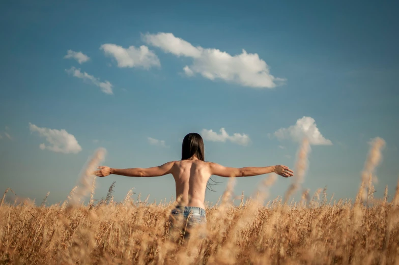 a shirtless person standing in a field full of tall grasses