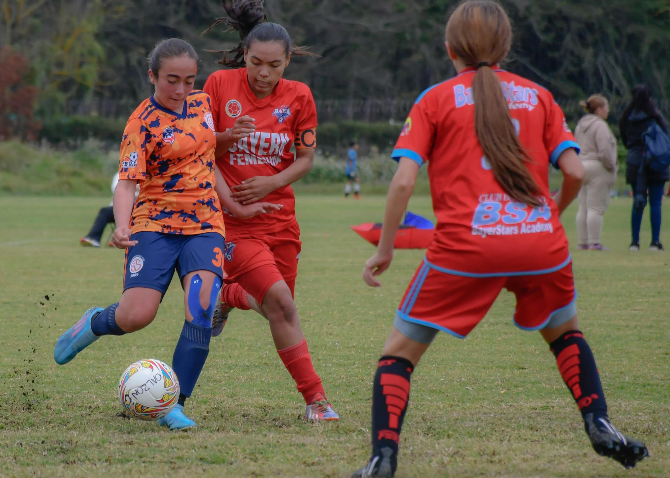 several girls in a field playing soccer with each other