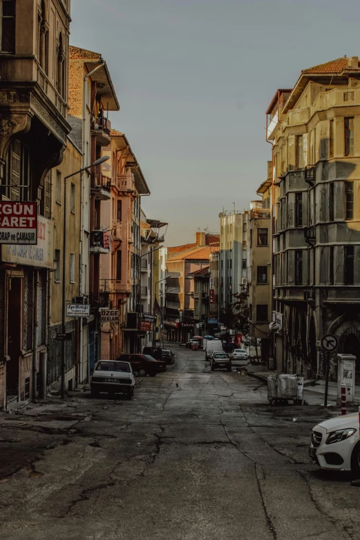 a deserted street lined with parked cars in front of buildings