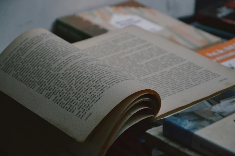 an open book laying on a table next to books