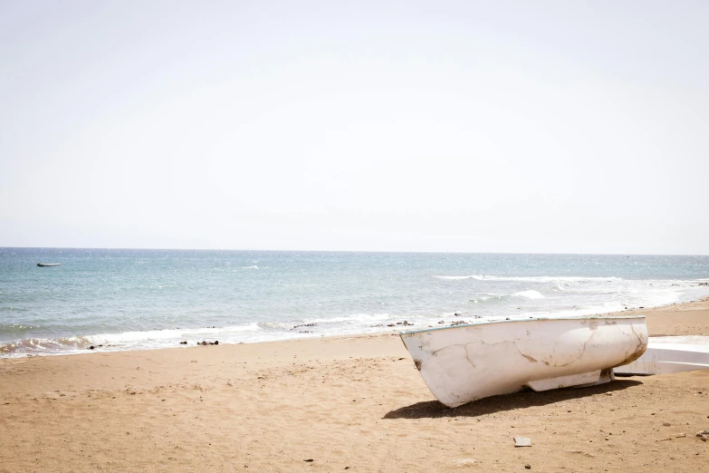 a boat is laying on the beach near the ocean