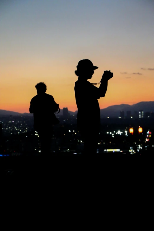 two people are standing in the distance silhouetted against the sunset