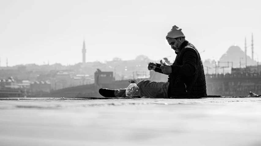 black and white pograph of a man sitting down using his cellphone