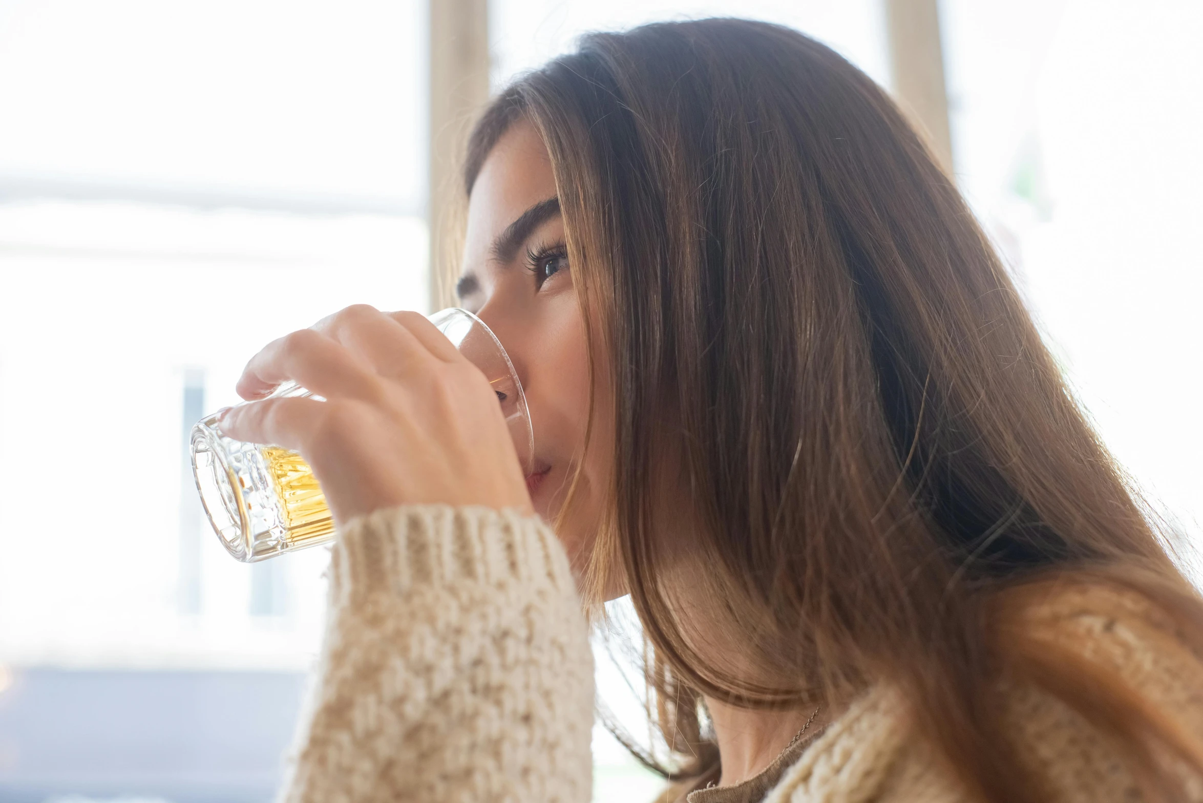 a woman drinking from a glass in her hands