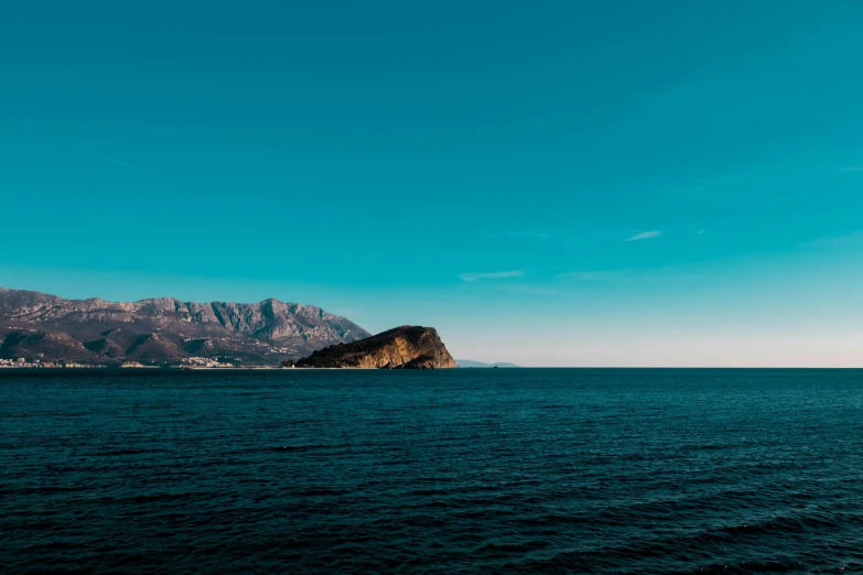 a sailboat on the ocean near a mountain