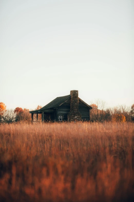 an old house sits in a field of dry grass